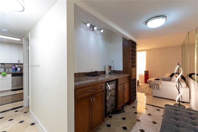 interior space featuring beverage cooler, baseboards, open floor plan, and stainless steel dishwasher