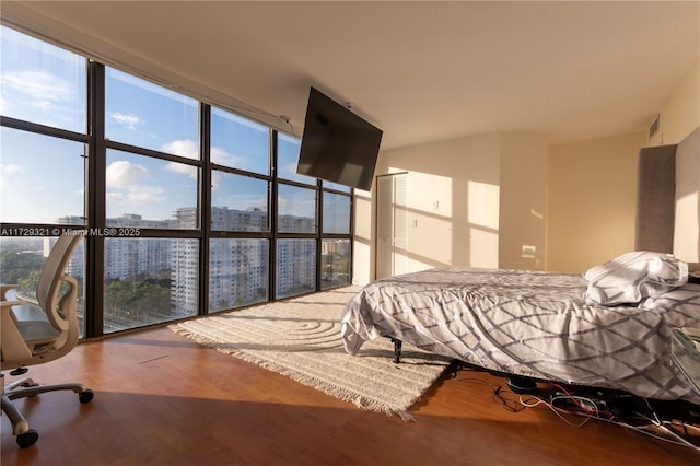 bedroom with expansive windows, multiple windows, wood finished floors, and visible vents