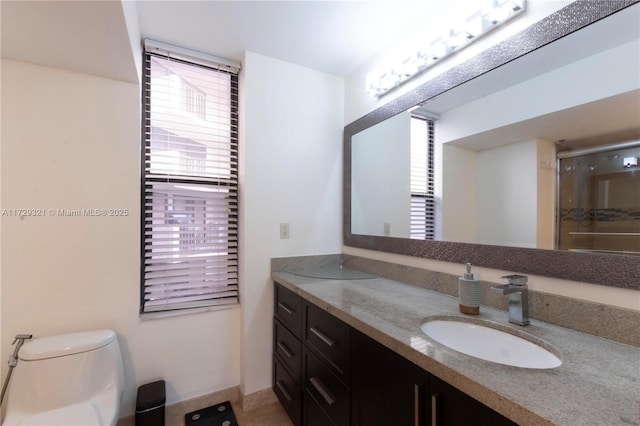 bathroom with a shower with door, vanity, and toilet