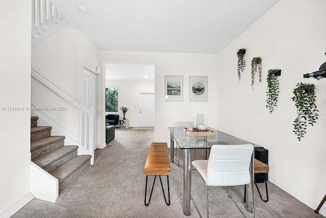 carpeted dining area with stairway and baseboards