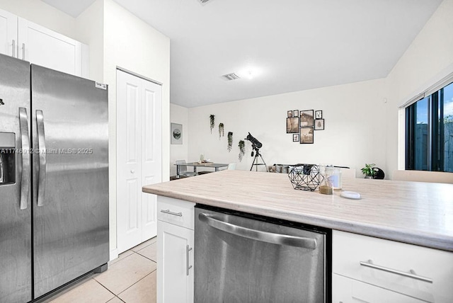 kitchen with light tile patterned floors, white cabinetry, appliances with stainless steel finishes, and light countertops