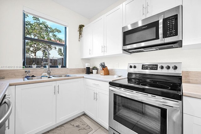 kitchen featuring stainless steel appliances, light countertops, and white cabinetry