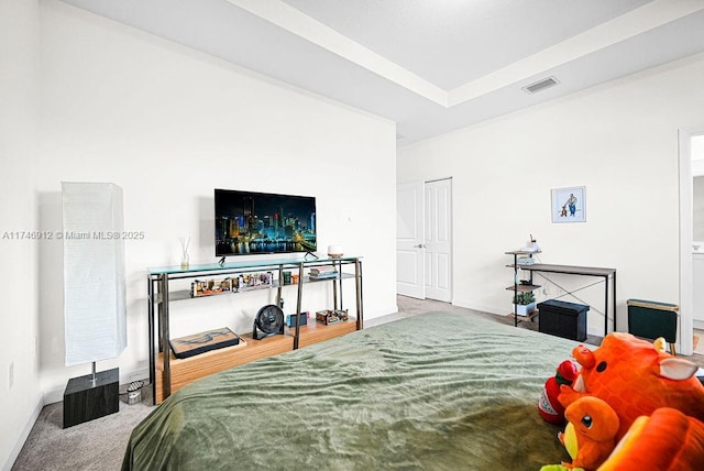 carpeted bedroom featuring baseboards, visible vents, and a raised ceiling