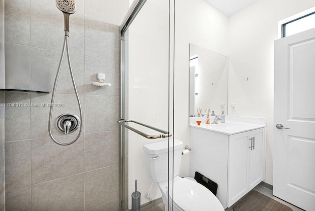 bathroom featuring a tile shower, vanity, and toilet