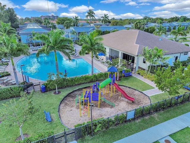 community jungle gym with a yard, fence, and a community pool