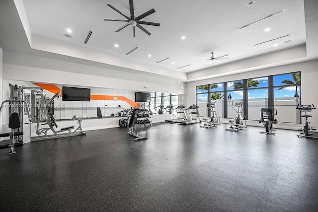 gym featuring ceiling fan, visible vents, baseboards, and a tray ceiling