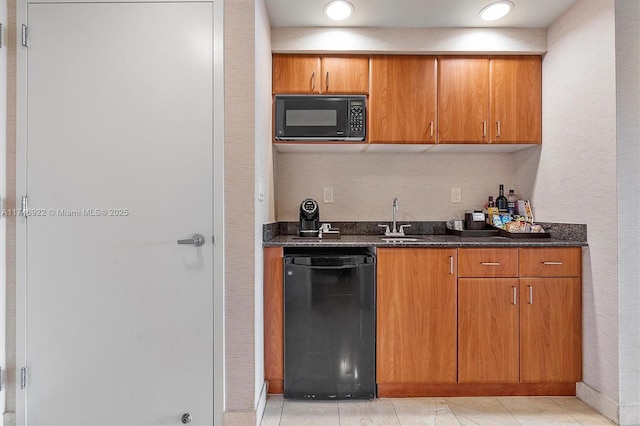 kitchen with dark stone counters, brown cabinets, a sink, and black appliances