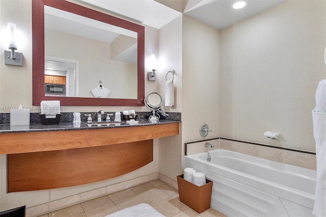 bathroom with tile patterned flooring, vanity, and a bath