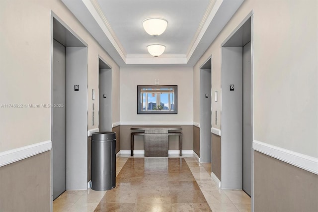 corridor featuring ornamental molding, elevator, a raised ceiling, and baseboards