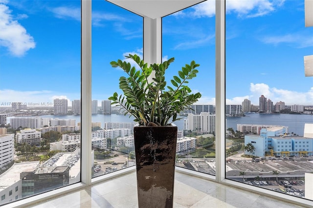 interior space with expansive windows, a water view, and a city view