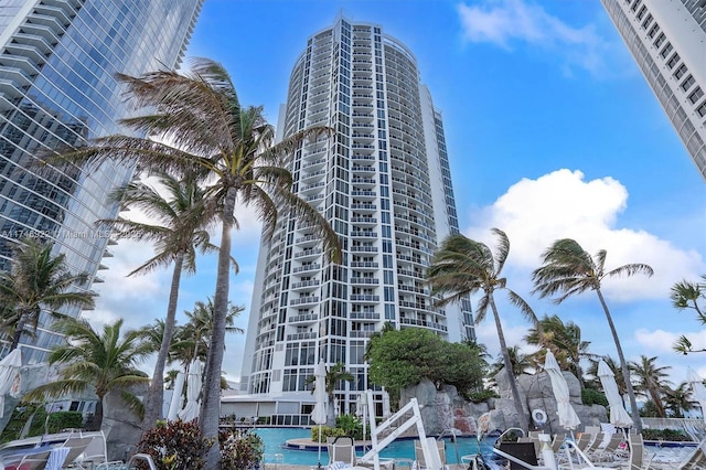 view of building exterior featuring a water view, a community pool, and a city view