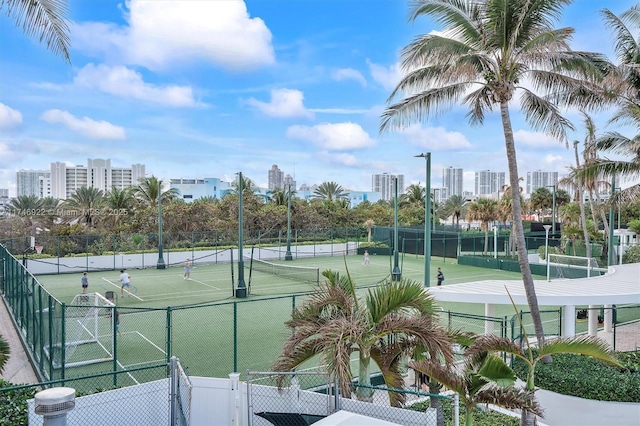 view of tennis court featuring a view of city and fence