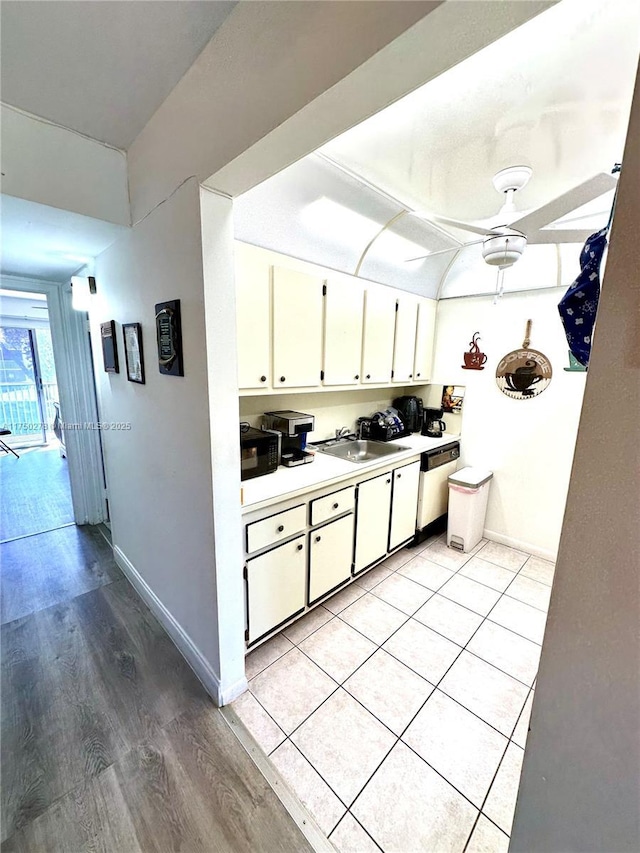 kitchen featuring white cabinets, black microwave, light countertops, and a sink