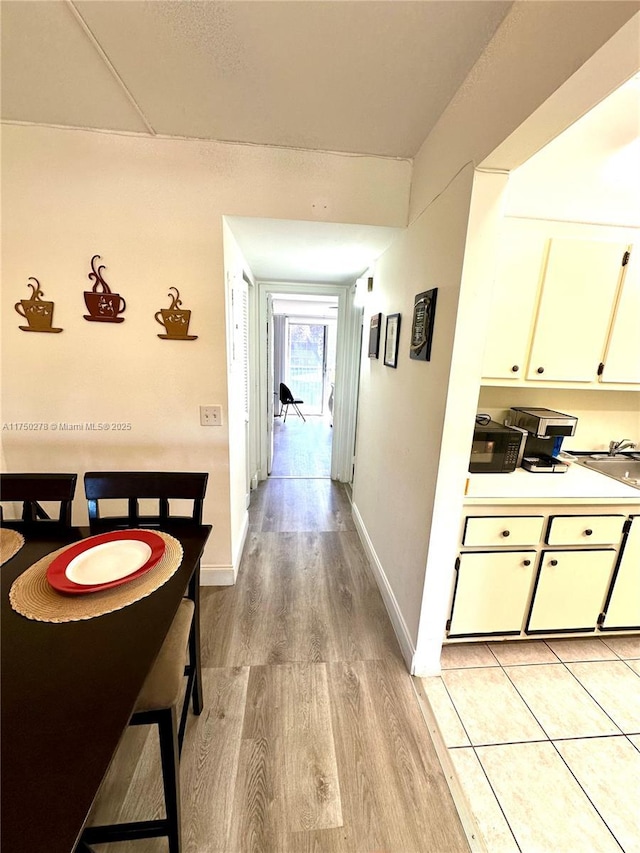 corridor featuring light wood-style flooring and baseboards