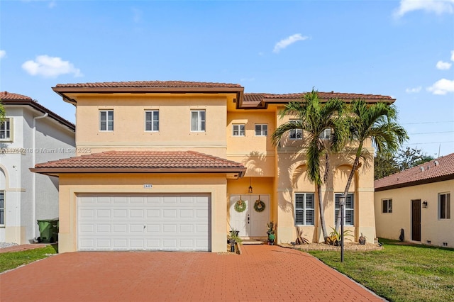 mediterranean / spanish-style home with a garage, a front yard, decorative driveway, and stucco siding