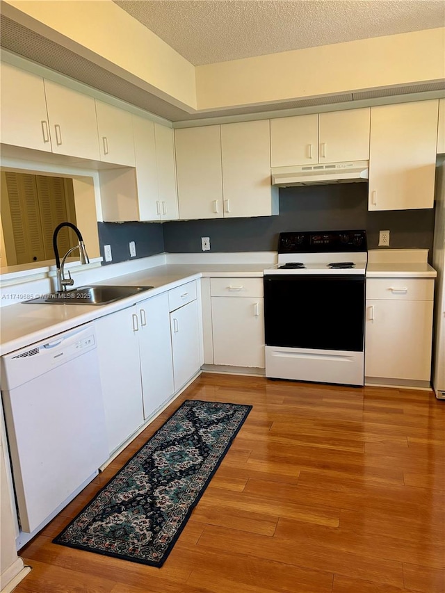 kitchen with electric range, white dishwasher, light countertops, under cabinet range hood, and a sink