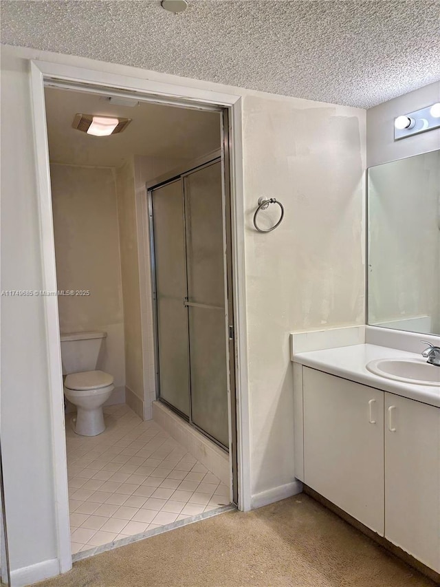 bathroom featuring toilet, a stall shower, a textured ceiling, and vanity