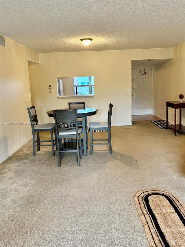 carpeted dining space with a textured ceiling