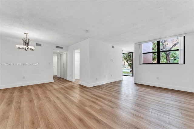 unfurnished room featuring a textured ceiling, visible vents, and light wood-style floors