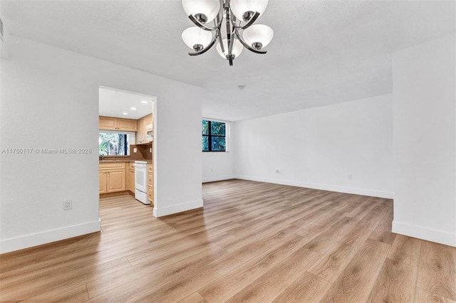 interior space with light wood-style flooring, baseboards, and an inviting chandelier