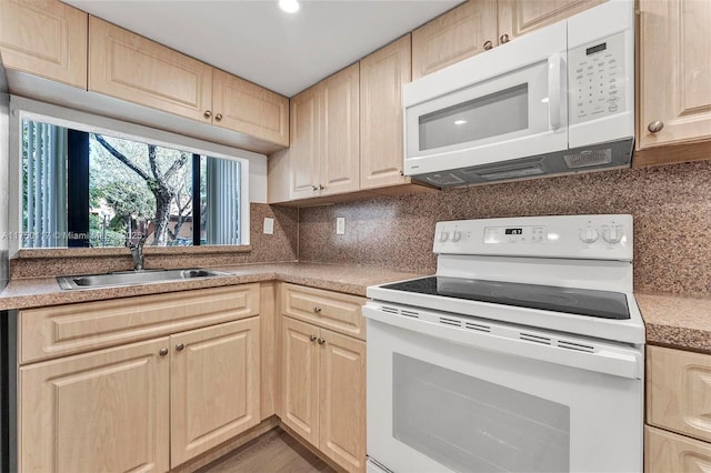 kitchen with light countertops, white appliances, a sink, and light brown cabinetry