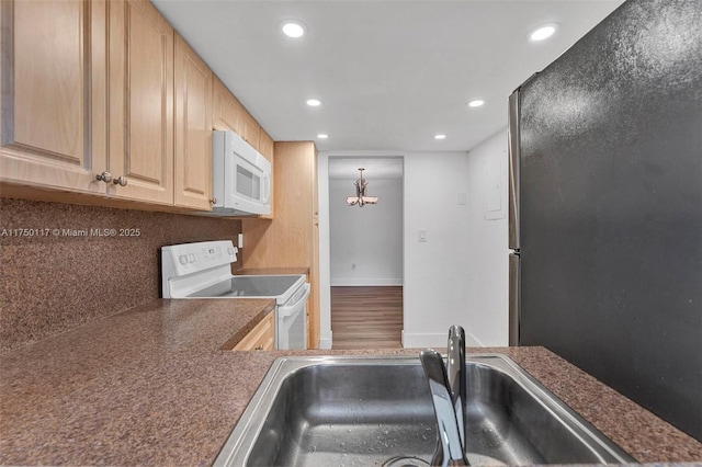 kitchen with dark countertops, white appliances, backsplash, and a sink