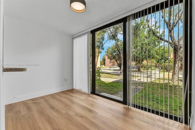 doorway featuring light wood-style flooring and baseboards