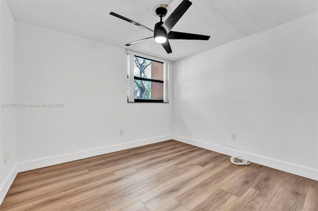 spare room featuring light wood-style floors, a ceiling fan, baseboards, and a textured ceiling