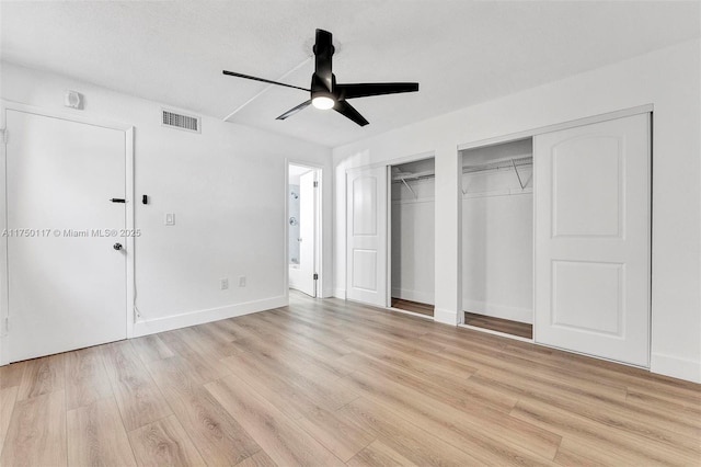 unfurnished bedroom with ceiling fan, visible vents, baseboards, multiple closets, and light wood finished floors