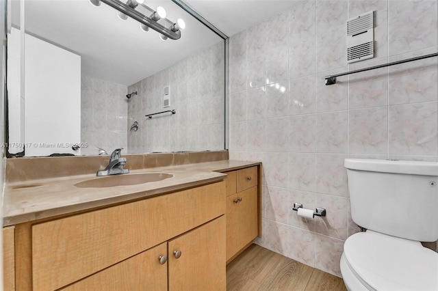 full bath featuring wood finished floors, tile walls, toilet, and vanity