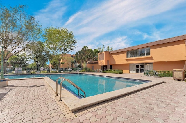 community pool with a patio area and fence