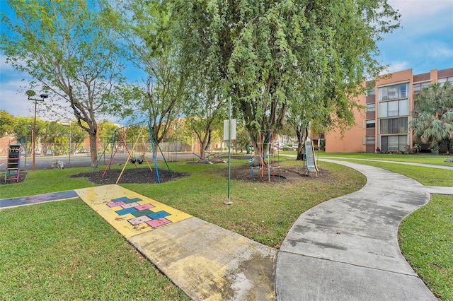 view of community featuring playground community, a lawn, and fence