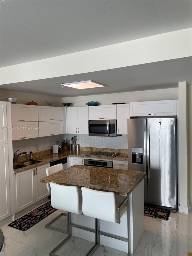 kitchen featuring marble finish floor, stainless steel appliances, a breakfast bar, and a sink