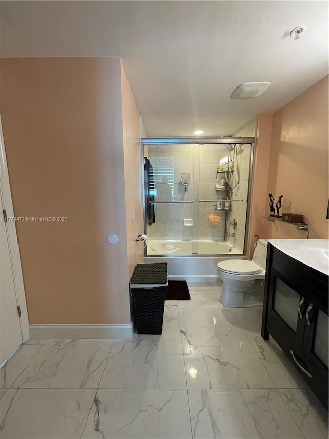 full bathroom featuring marble finish floor, toilet, combined bath / shower with glass door, vanity, and baseboards