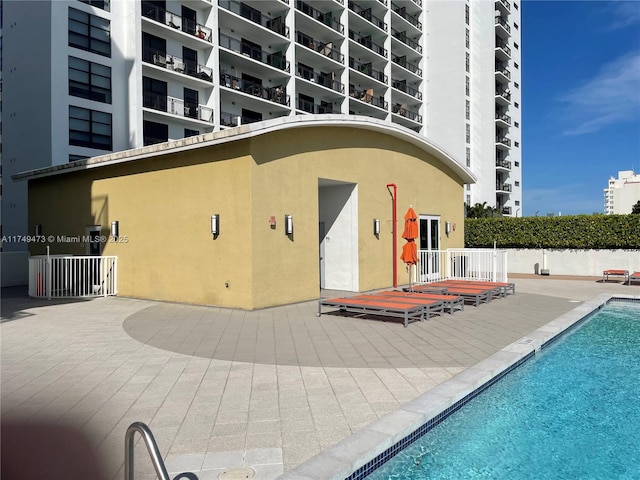 rear view of property with fence, a community pool, and stucco siding