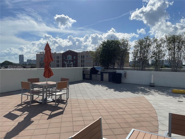 view of patio / terrace featuring a city view, fence, and an outdoor kitchen