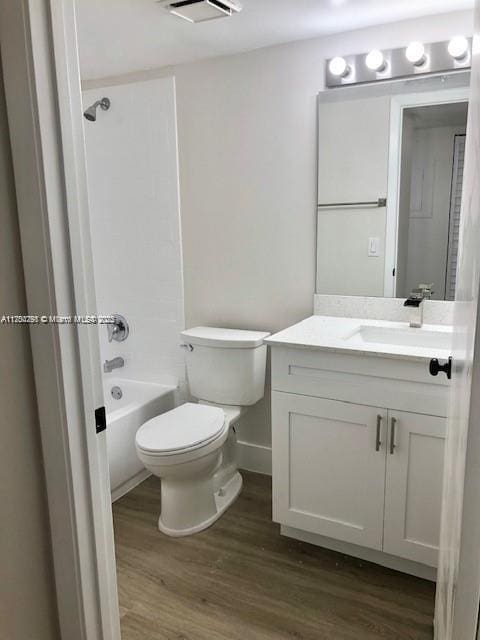 bathroom featuring shower / bathing tub combination, toilet, vanity, wood finished floors, and baseboards