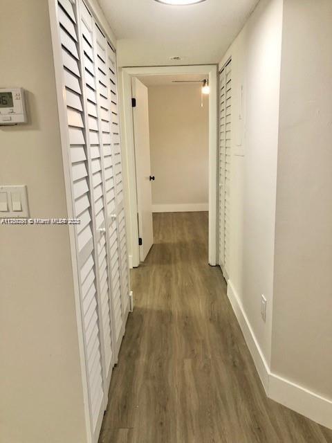 hall with dark wood-style flooring and baseboards