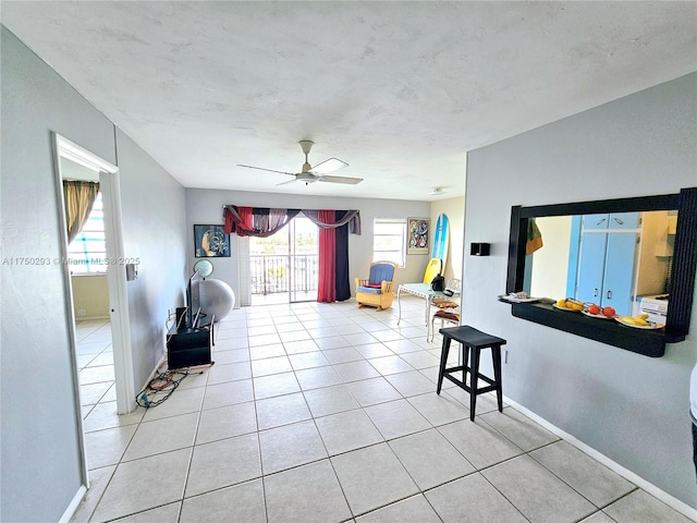 interior space with light tile patterned floors, a ceiling fan, and baseboards