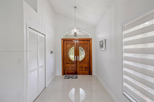 entryway featuring baseboards, vaulted ceiling, and light tile patterned flooring