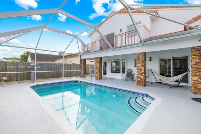 view of pool featuring glass enclosure, a patio area, fence, and a fenced in pool