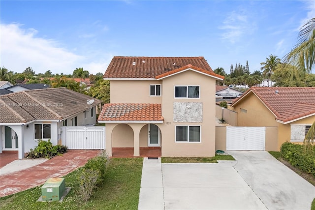 mediterranean / spanish house featuring a tiled roof, a gate, and stucco siding