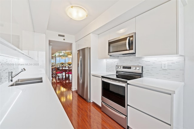 kitchen featuring white cabinets, appliances with stainless steel finishes, light countertops, and a sink