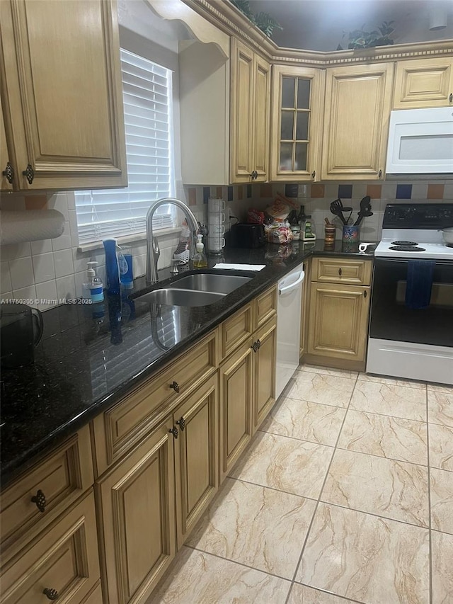 kitchen featuring glass insert cabinets, dark stone counters, white appliances, and a sink