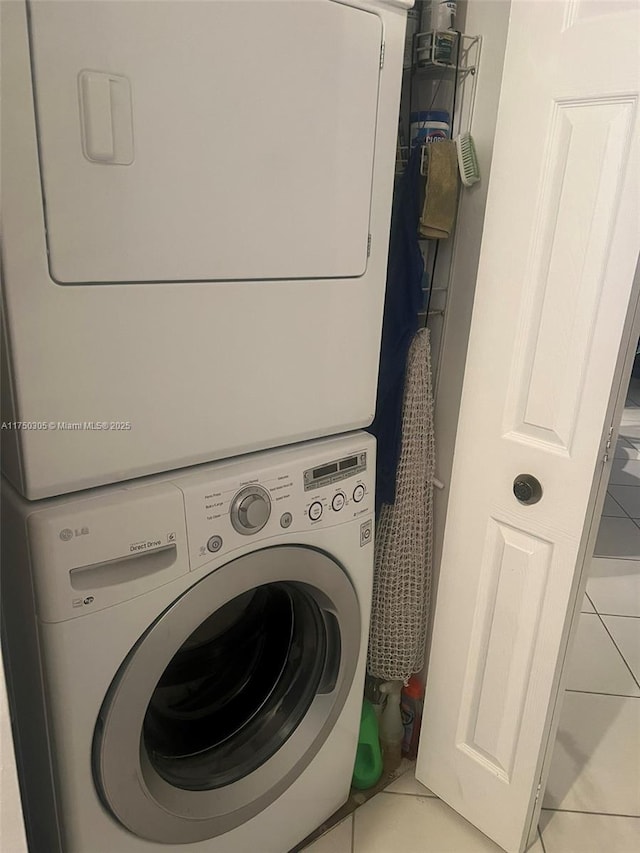 washroom featuring laundry area, stacked washing maching and dryer, and light tile patterned floors