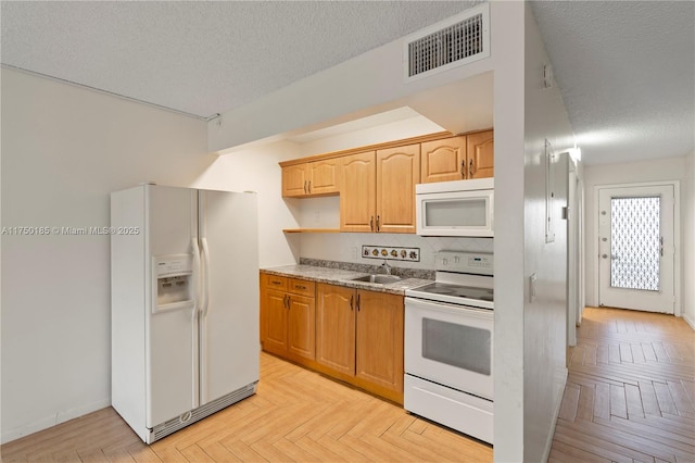 kitchen featuring a textured ceiling, white appliances, a sink, visible vents, and light countertops