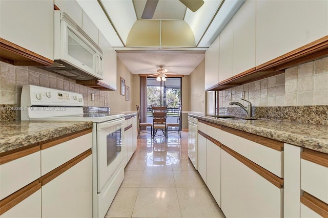 kitchen featuring white appliances, light stone counters, white cabinetry, a sink, and light tile patterned flooring