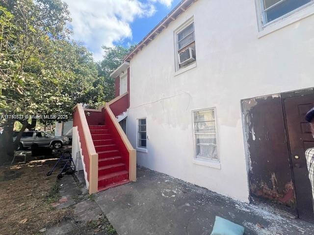 view of side of property featuring stairs, cooling unit, and stucco siding