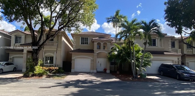 view of front of property with a tile roof, driveway, an attached garage, and stucco siding