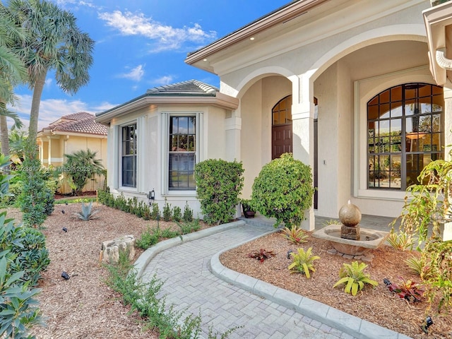 view of exterior entry featuring a tiled roof and stucco siding